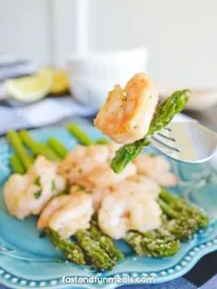 shrimp and asparagus being held up by a fork
