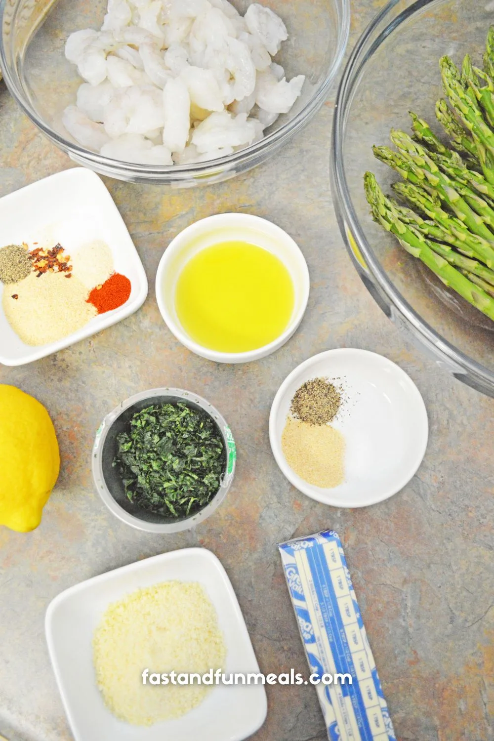 ingredients set up to make sheet pan shrimp and asparagus completed dish on a blue plate